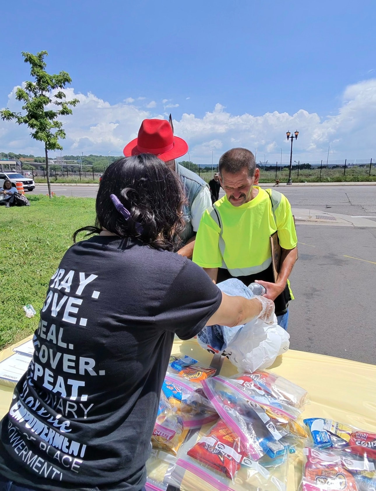 Volunteer handing out food bags and smiling at a community outreach event